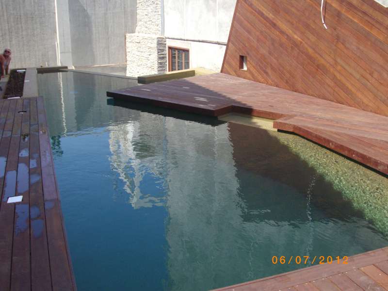 Αλκαλικότητα νερού πισίνας. Μια πισίνα με επένδυση ξύλου να κυριαρχεί στο περιβάλλοντα χώρο