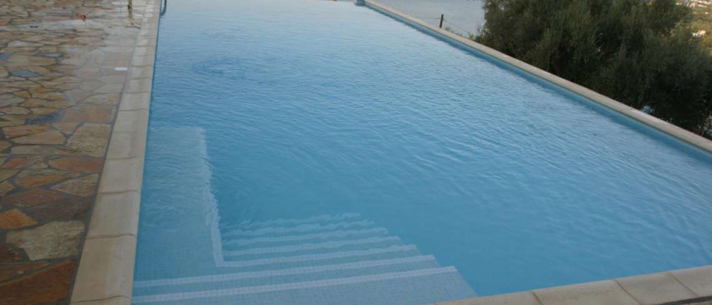 ΕΝΕΡΓΟ ΟΞΥΓΟΝΟ ΥΓΡΟ ΣΤΗ ΠΙΣΙΝΑ. Μια πισίνα με καταρράκτη με φόντο τη θάλασσα.